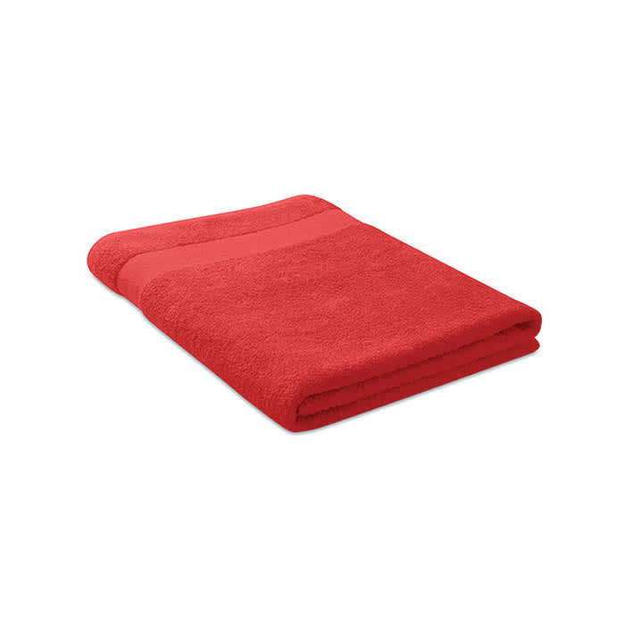 A red towel neatly folded with a textured band across the top. It has a soft, fluffy appearance.