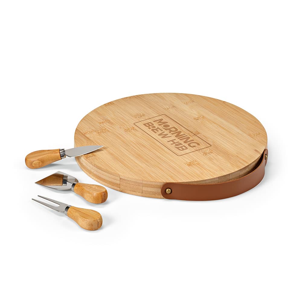 A round bamboo cheese board with a leather handle and three wooden-handled cheese utensils.