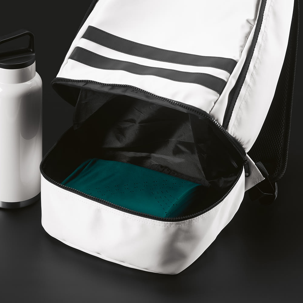 A white backpack with reflective black strips, partially open, revealing a teal item inside and a drink bottle beside it.