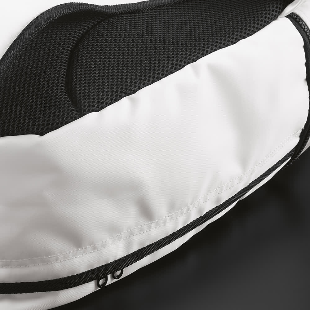 A white backpack featuring a zippered pocket and mesh detailing on the back. It has reflective front strips.