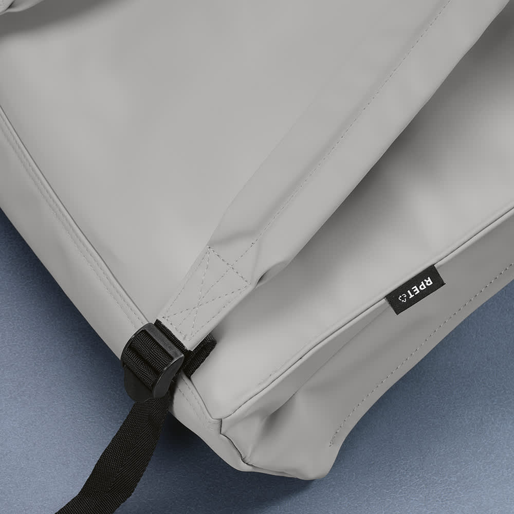 A grey backpack with adjustable straps, featuring a logo and made from rPU and rPET materials. 