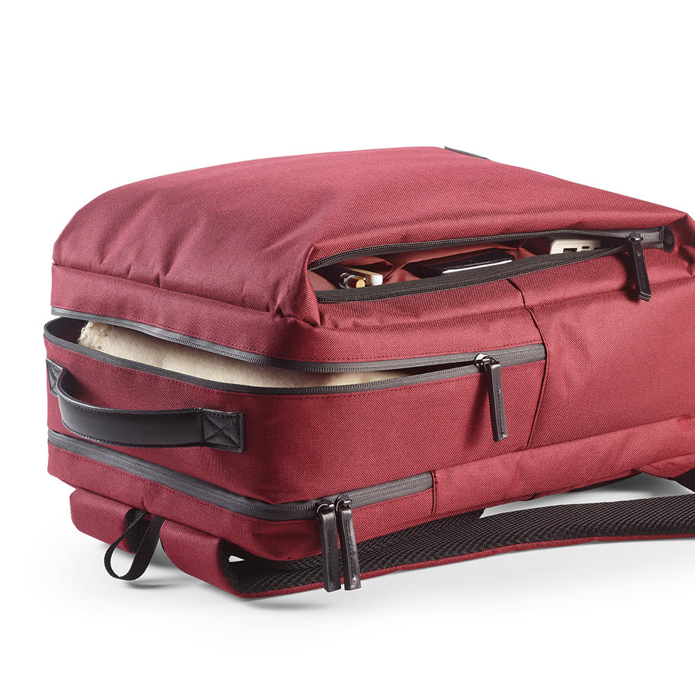 A red Oslo Backpack with waterproof zippers and compartments for a 17" laptop. Features a logo on the exterior.