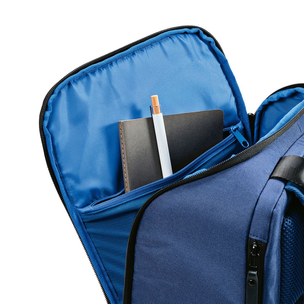 A navy blue backpack with a front pocket, containing a notebook and a pen. It has a branding logo.