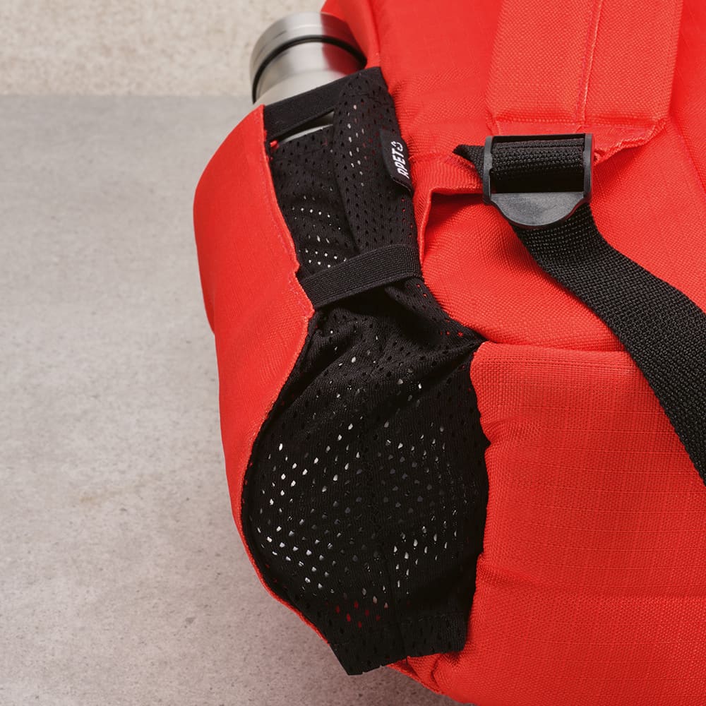 A red backpack features a side mesh pocket, designed to hold a drink bottle and adjustable straps.