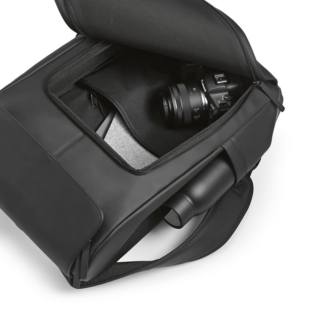 A black backpack with an open compartment revealing a camera and storage space inside.