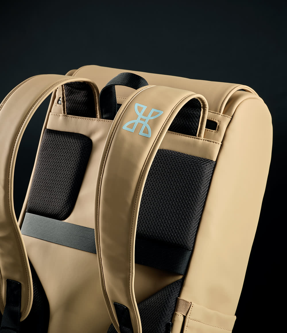 A beige backpack featuring adjustable straps and a logo on the front. Suitable for a 15.6" laptop.