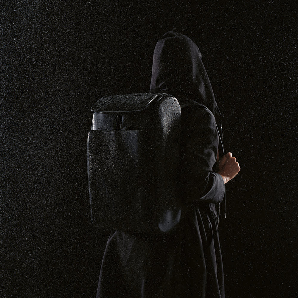A black Lisbon Backpack 20L rPU, designed to fit a 15.6" laptop, is worn on the back of a person.