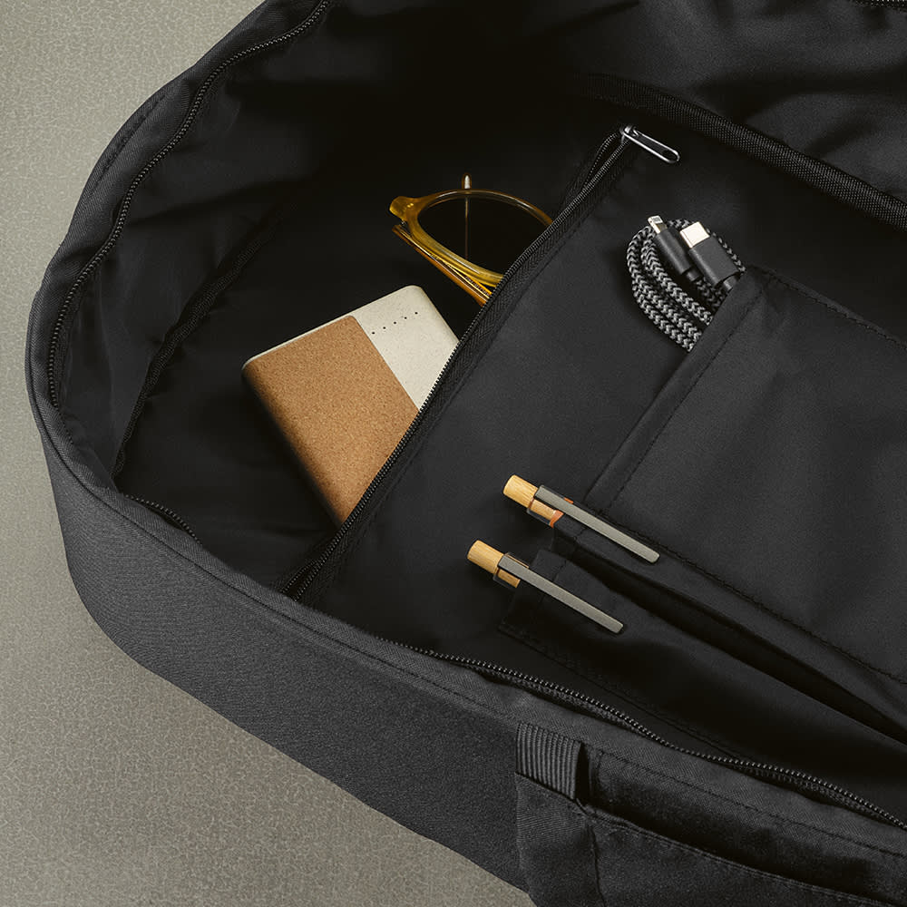 A black backpack featuring a spacious interior with a notebook, sunglasses, and two pens inside.