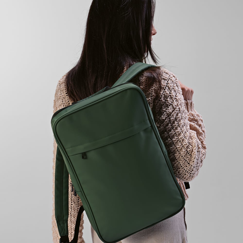A green backpack with adjustable straps, featuring a front pocket, suitable for carrying a laptop.