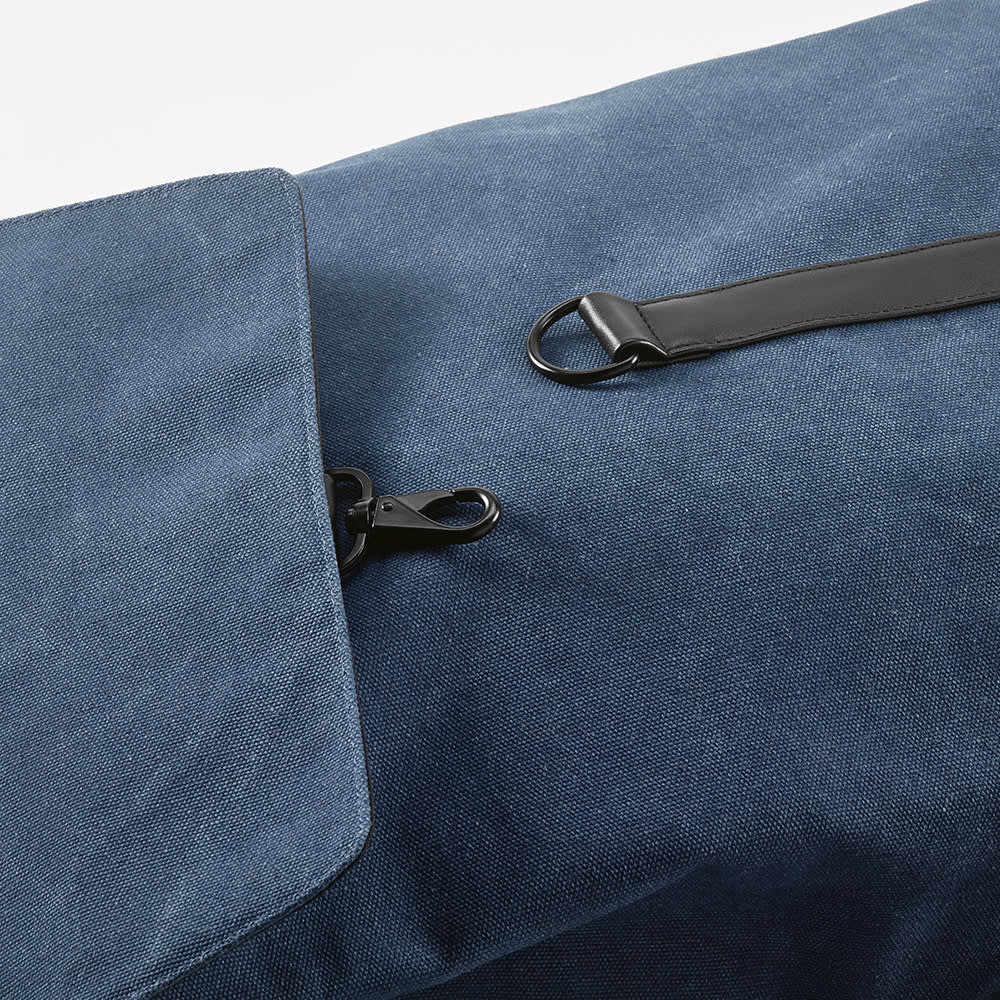 A blue canvas backpack featuring a hook closure and a clip. Suitable for a 17" laptop. Includes a logo.