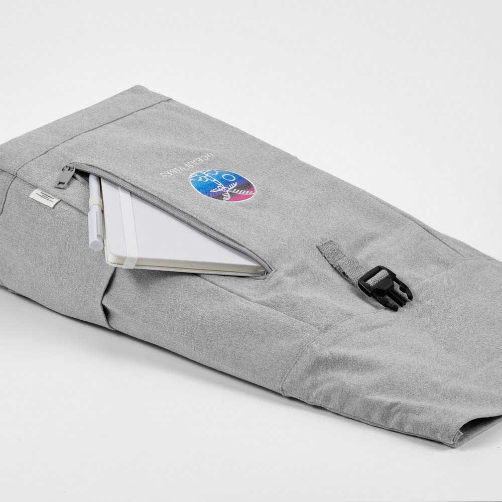 A grey roll-top backpack with a buckle closure, featuring an external zip pocket and a logo.