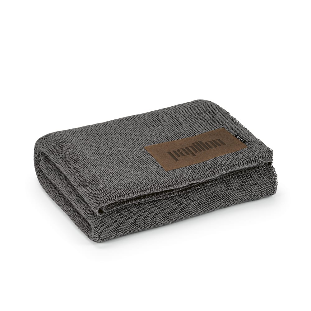 A grey blanket folded neatly, featuring a customisable patch and a small logo.