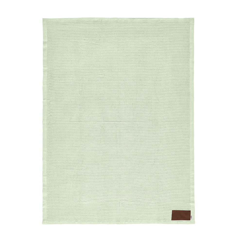 A light green knitted blanket with a brown patch, designed for customisation. It features a textured surface.