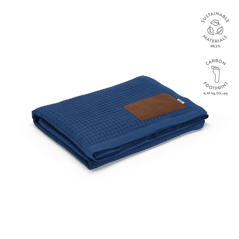 A folded navy blue Giotto blanket with a brown customised patch, featuring a textured pattern.