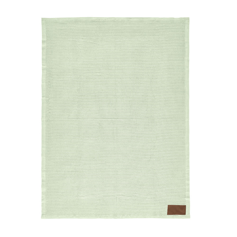 A green Giotto blanket with a textured pattern and a brown patch, featuring a branding logo.