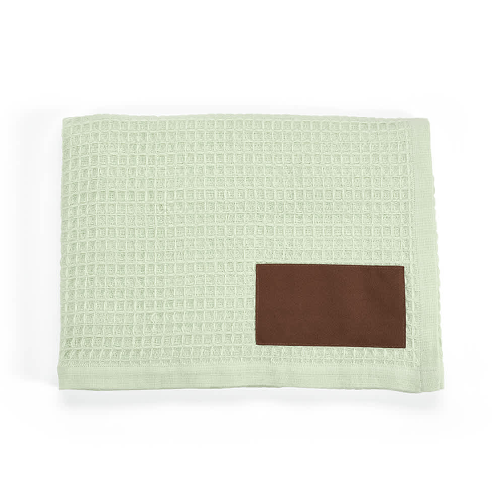 A mint green blanket with a textured pattern and a brown customizable patch.