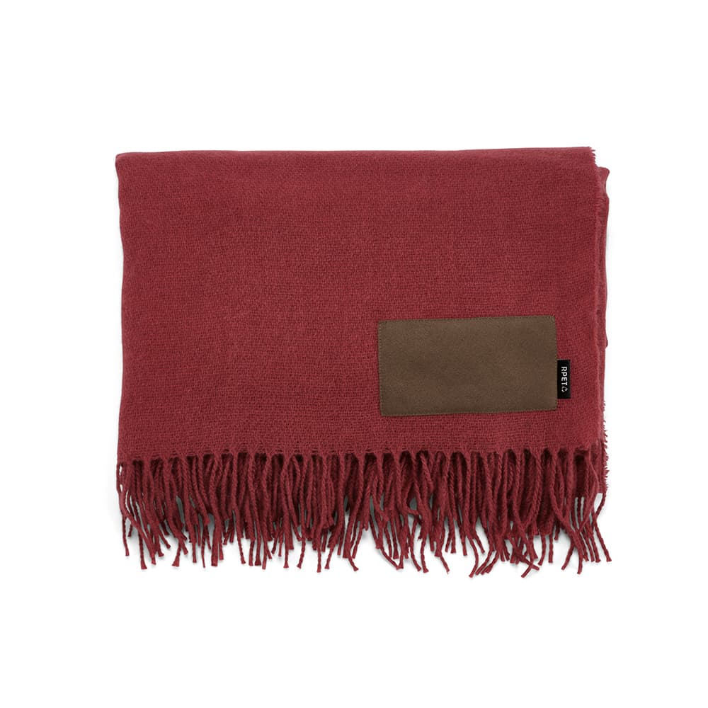 A burgundy blanket with fringed edges and a customisable patch. It features a discreet logo.
