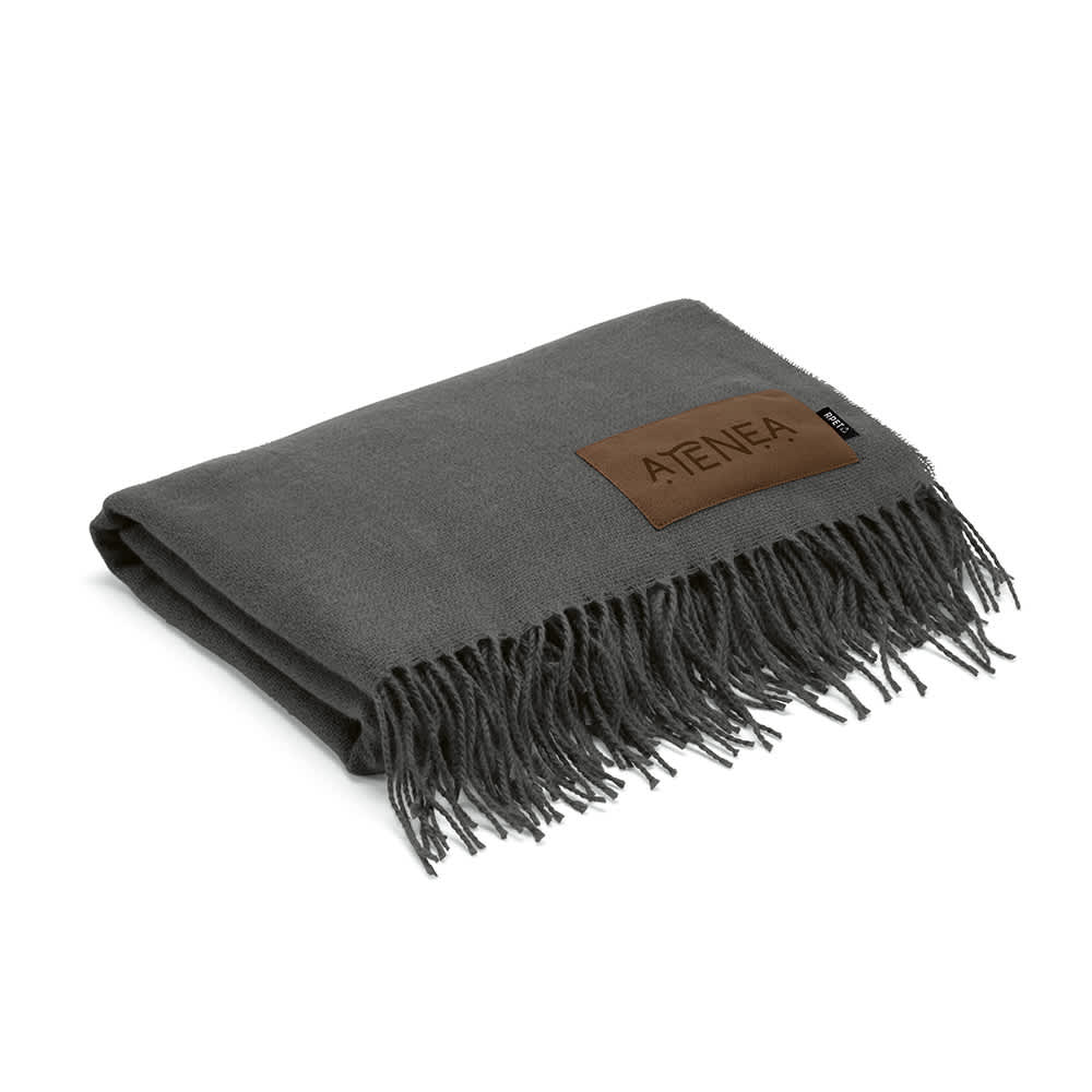 A grey blanket featuring fringe edges and a customisable patch with a logo.