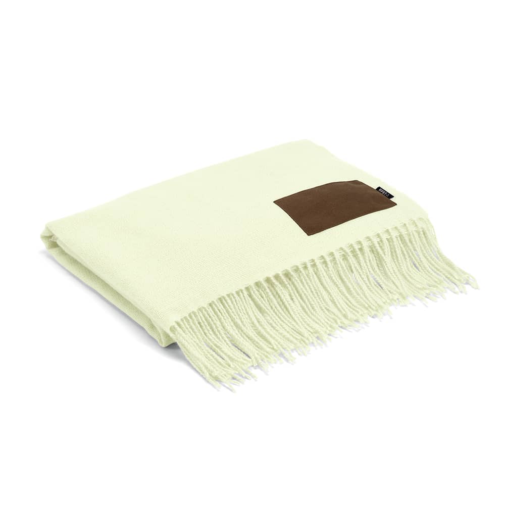 A light green blanket with fringed edges and a brown patch. Features a logo on the patch.