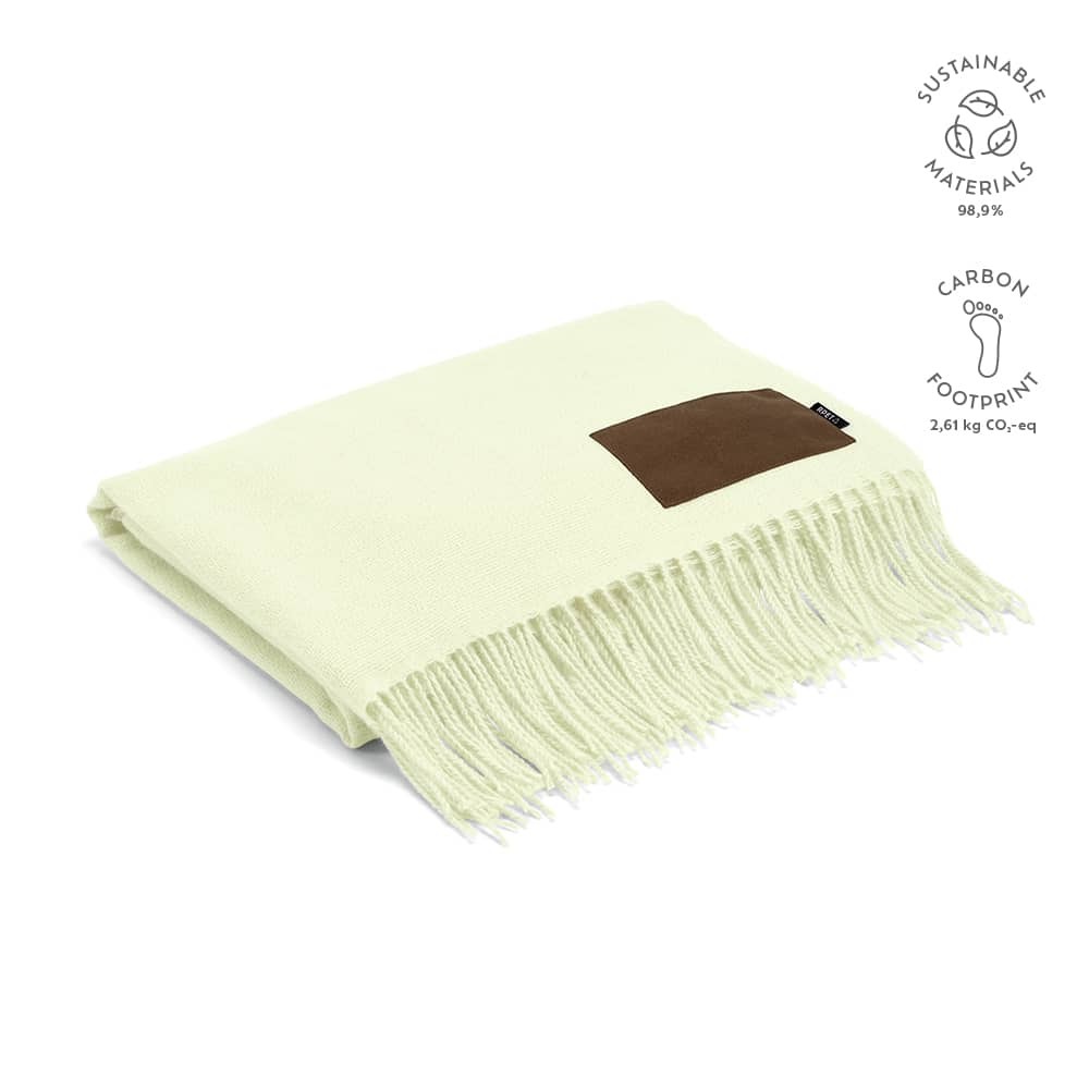 A pale green blanket made from sustainable materials, featuring a brown customisable patch and fringe detailing.