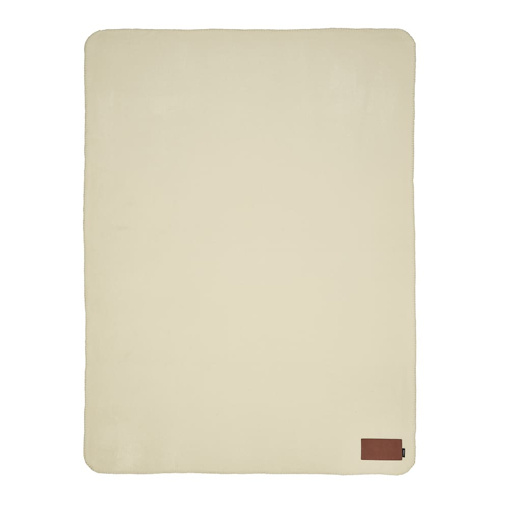 A cream-coloured blanket with a textured surface and a small branded patch in one corner.