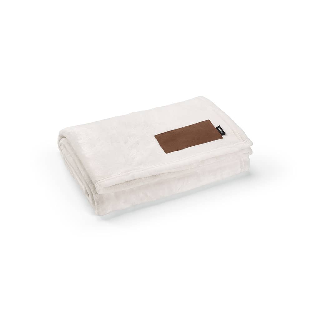 A folded cream blanket with a brown customisable patch. The blanket is made of soft fabric, featuring a logo.