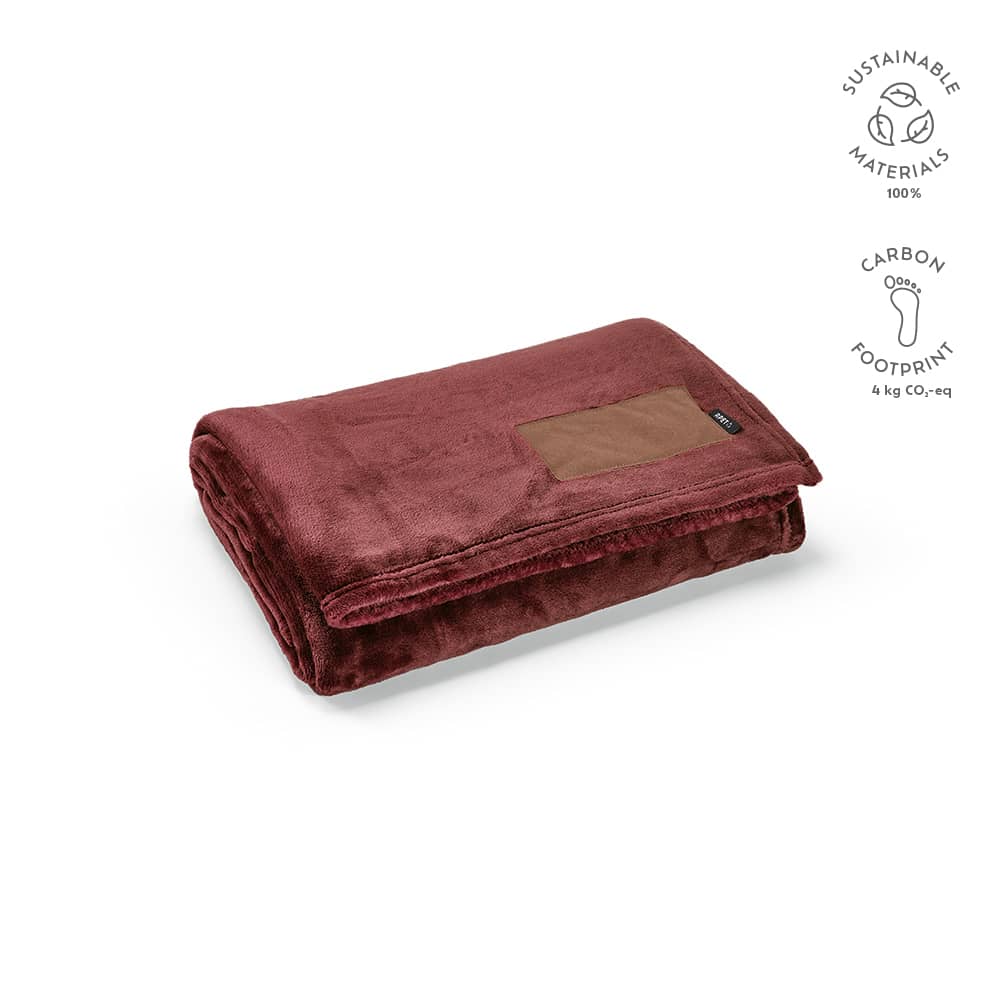 A maroon blanket made from sustainable materials, featuring a customisable patch and a soft texture.