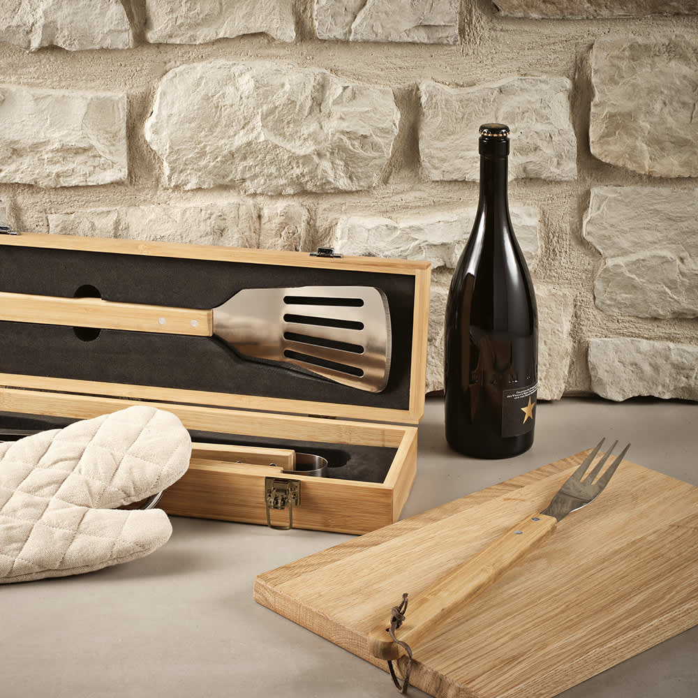 A bamboo barbecue set featuring a spatula, fork, and case, alongside an oven mitt and a drink bottle.
