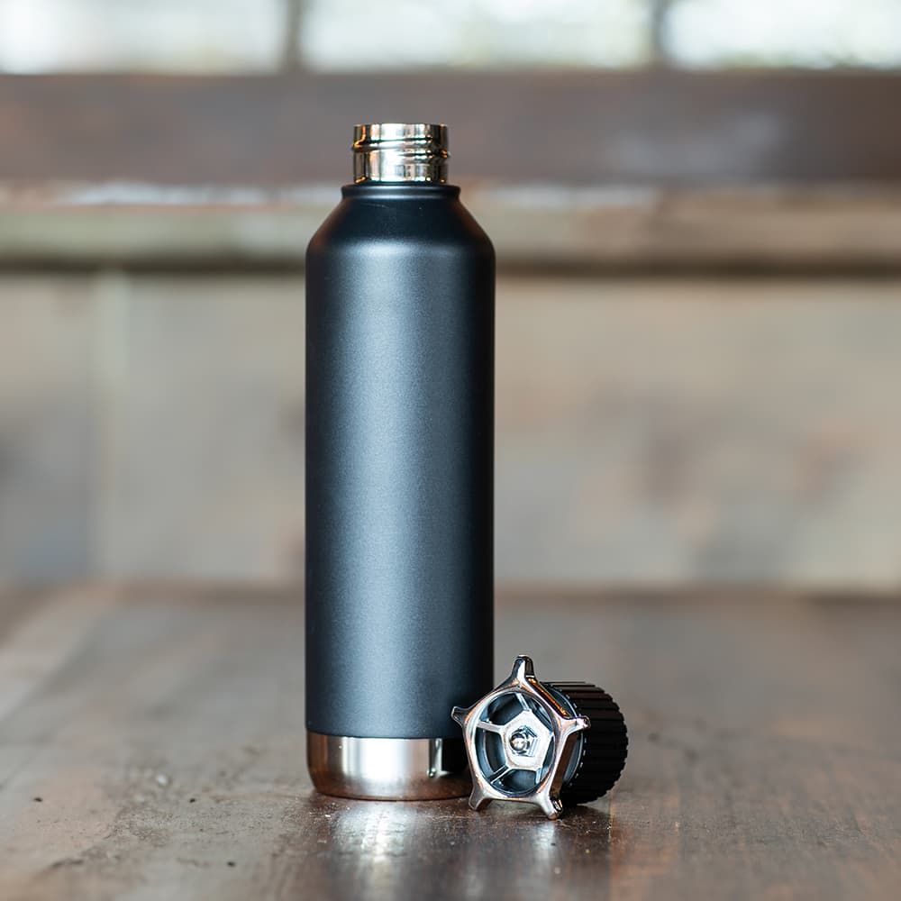 A drink bottle in matte black with a stainless steel base and a wheel-shaped lid. The bottle is double-walled and leakproof.