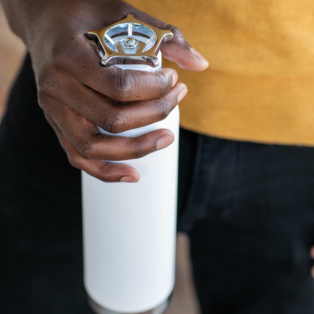 A drink bottle with a white body and a wheel-shaped silver lid, held by a hand. It features a logo.
