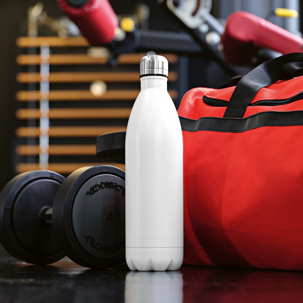 A drink bottle in white, featuring a stainless steel lid, stands next to a red gym bag and weights.