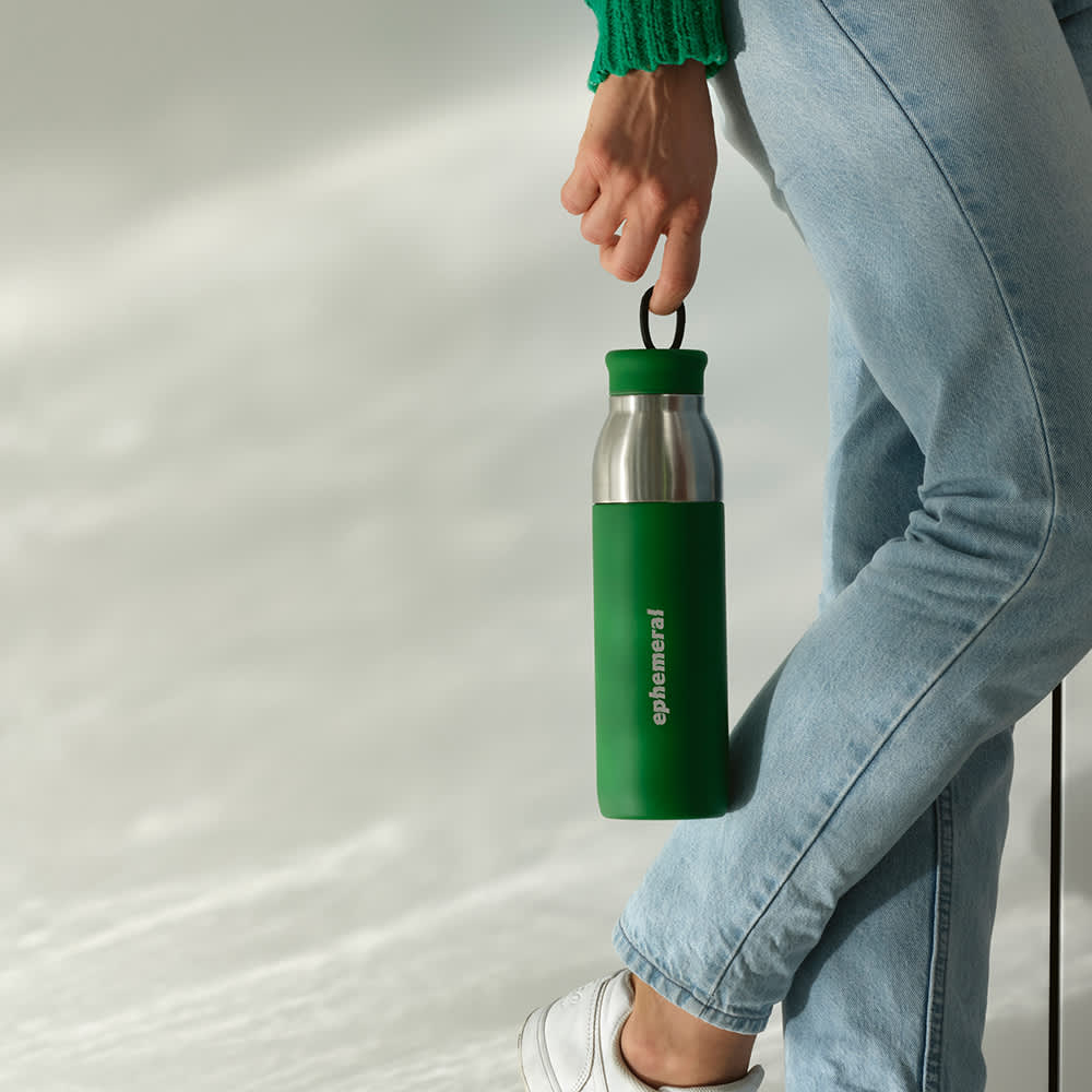 A drink bottle with a green exterior and stainless steel interior, featuring a logo and a leakproof cap.