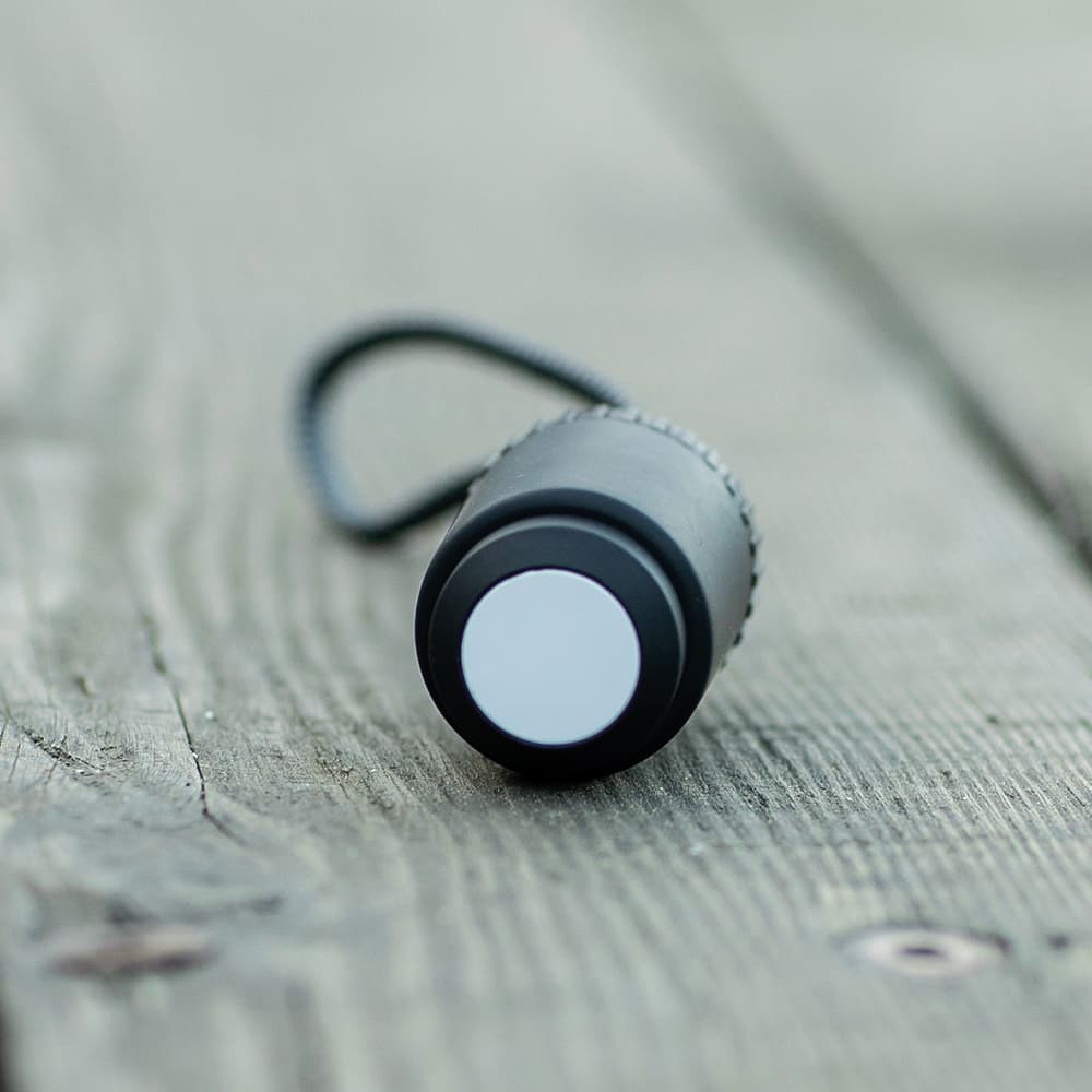 A black and silver cylindrical cable with a looped attachment on a wooden surface.