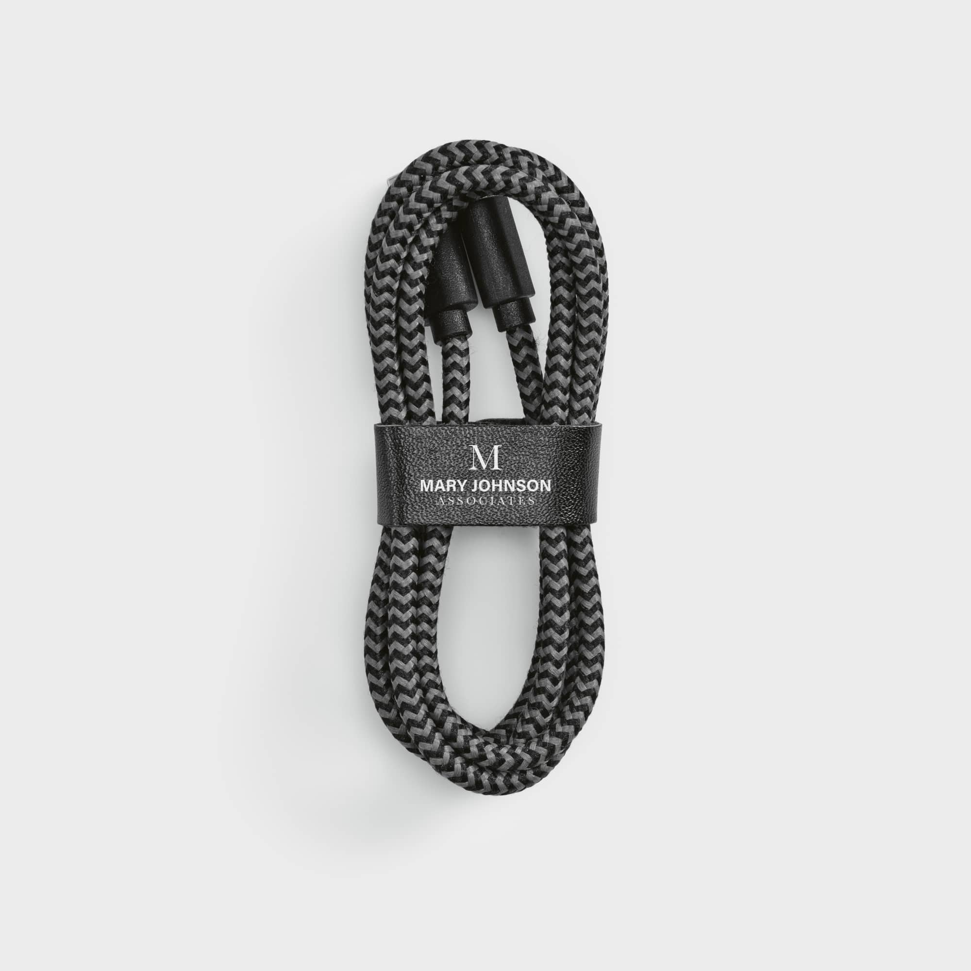 A braided black USB-C to USB-C cable, neatly wrapped with a black leather strap featuring a logo.