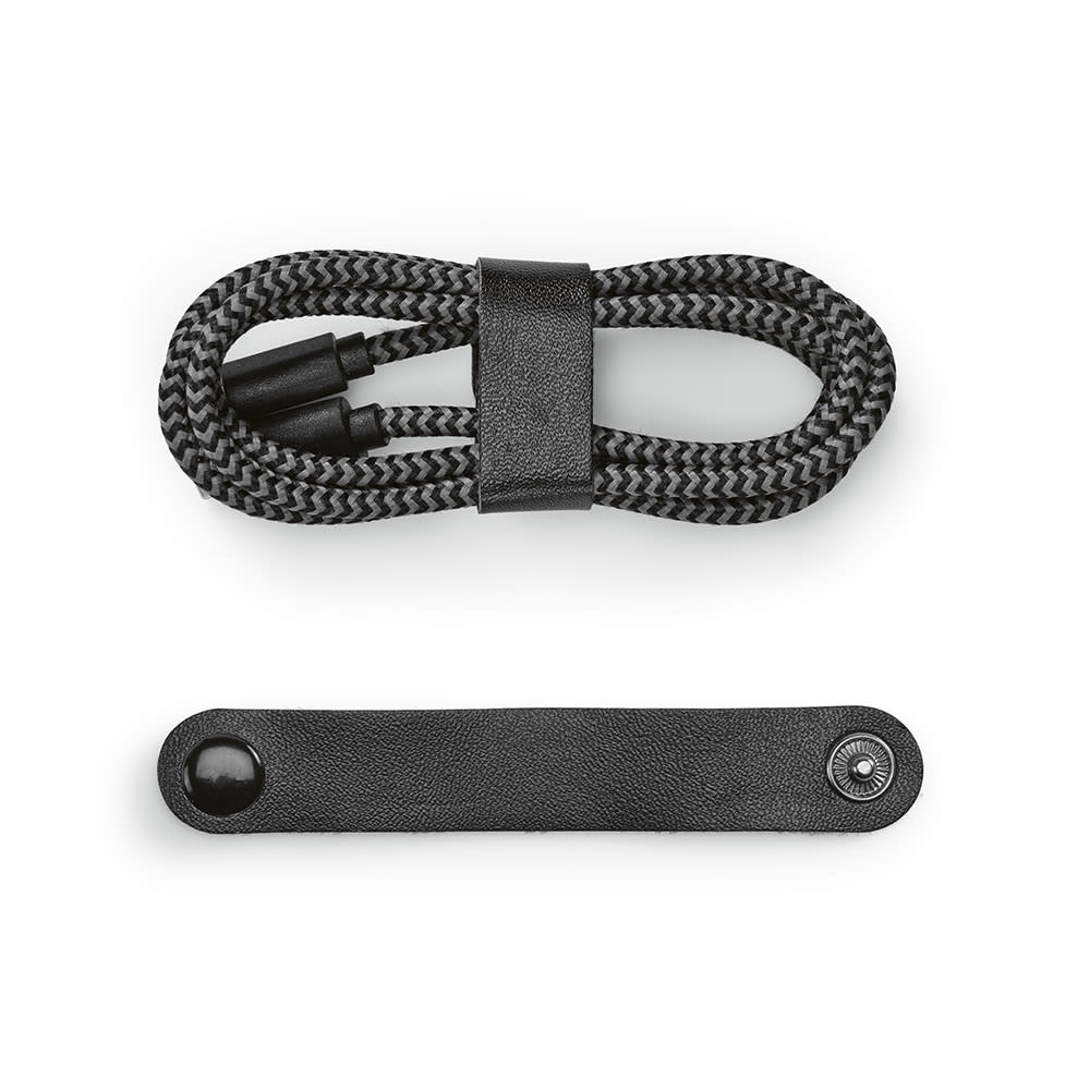A black and grey braided USB-C to USB-C charging cable, neatly coiled with a black leather strap.