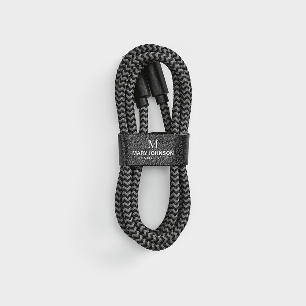 A black and grey braided USB-C to USB-C cable, neatly coiled and secured with a black strap featuring a logo.