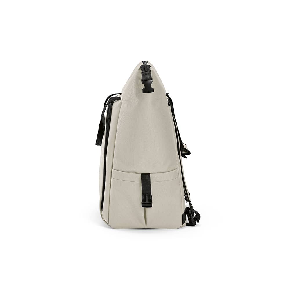 A beige cooler bag with a front pocket, two side pockets, and adjustable straps. It has a logo on the side.