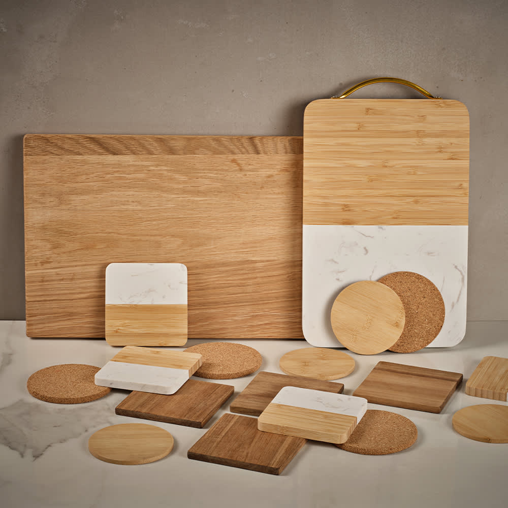 A set of four coasters made of bamboo and marble, featuring various round and square shapes in natural wood tones.