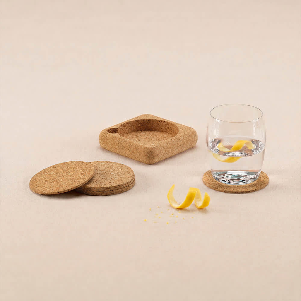 A set of six cork coasters in natural colour, with a square coaster for an organiser and a glass of water.