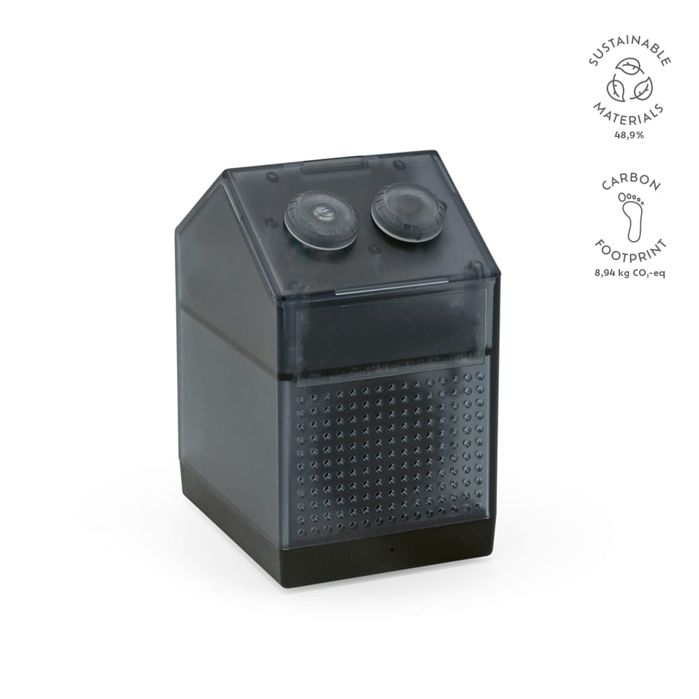 A compact grey speaker with two circular buttons on top, featuring a textured front panel and a branding logo.