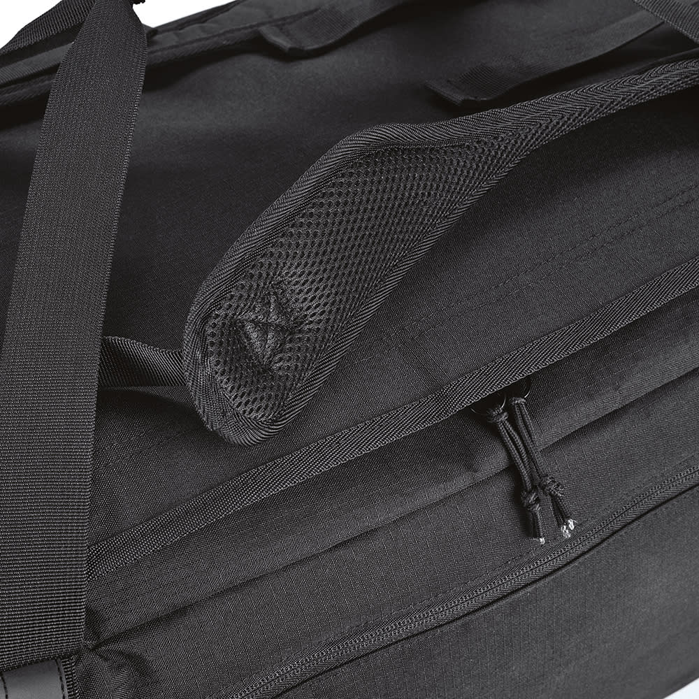 A black gym bag with a zippered compartment and a mesh pocket on the side. It features durable fabric and reflective strips.