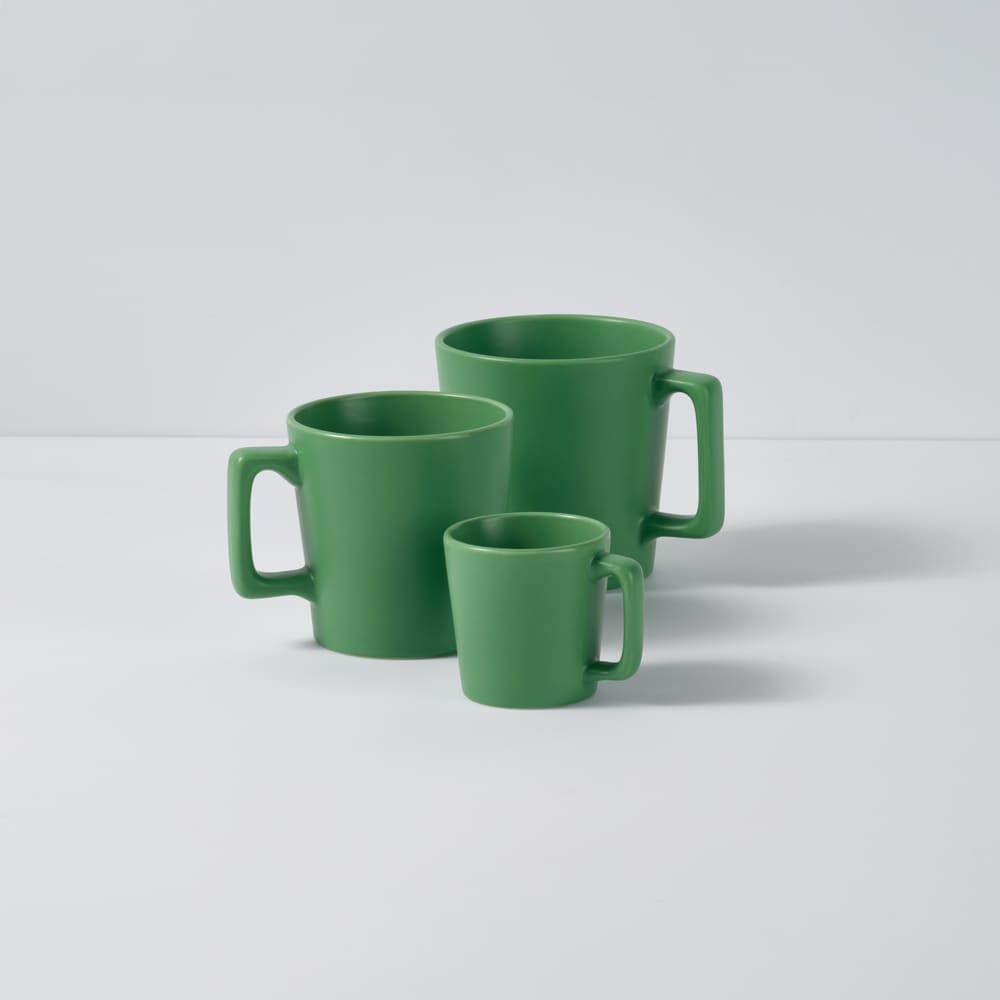 A set of green ceramic mugs in varying sizes with a matte finish and smooth surfaces.