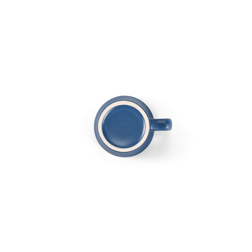 A ceramic mug with a matte blue finish and a contrasting light-coloured rim, featuring a handle.