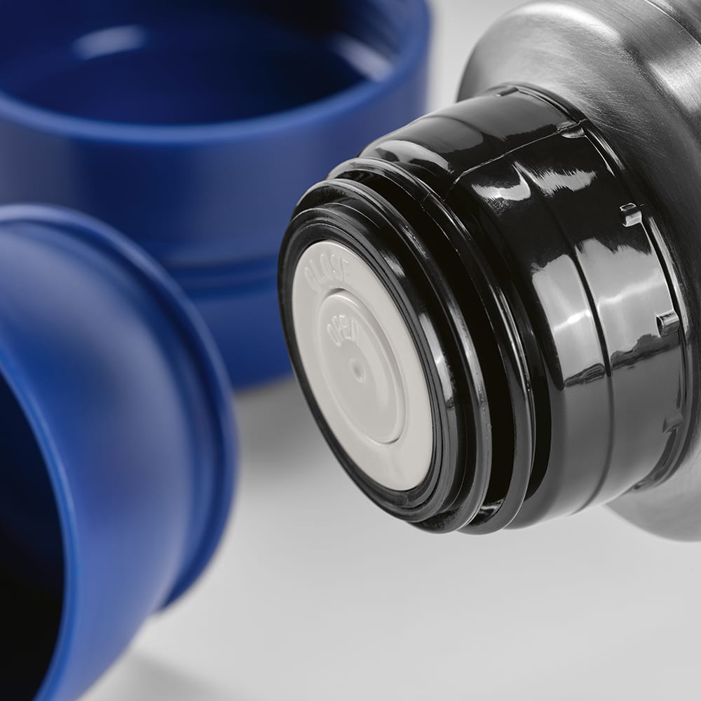 A drink bottle with a black lid and a blue cup beside it, featuring a silver carabiner.