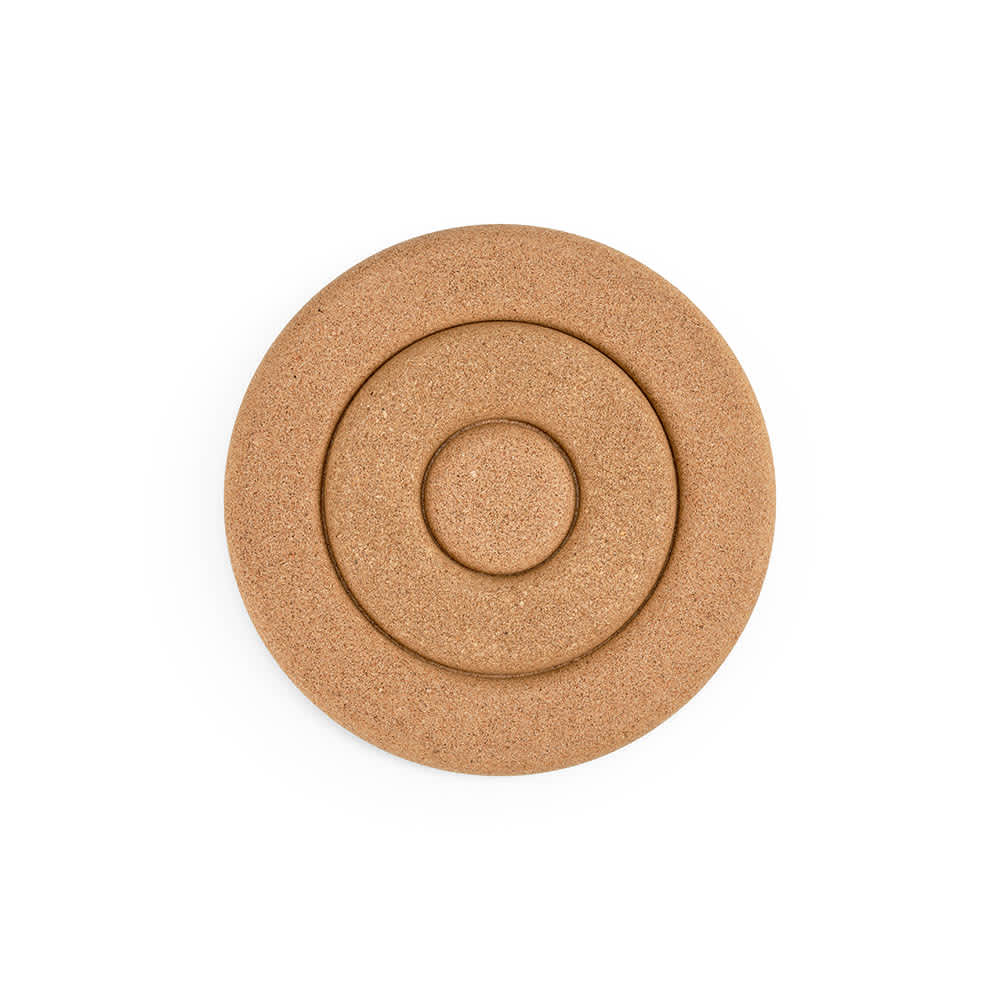 A round cork trivet in a natural tan colour, featuring concentric circular designs. Made in Portugal.