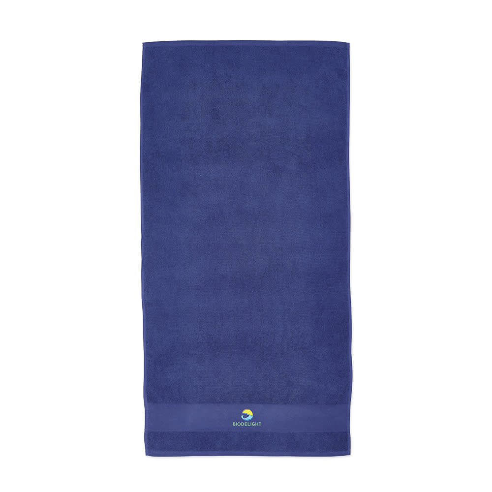A purple towel made of cotton with a textured surface and a logo at the bottom.
