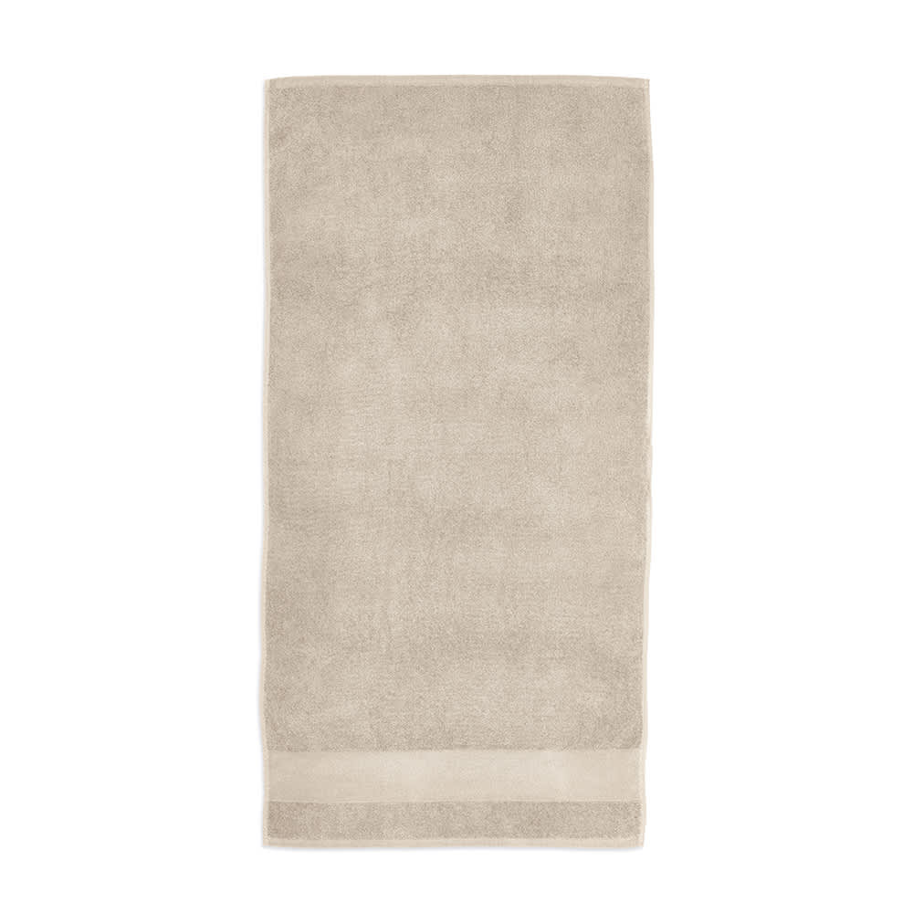 A beige cotton towel with a soft texture and a subtle trim, featuring a logo. Made in Portugal.