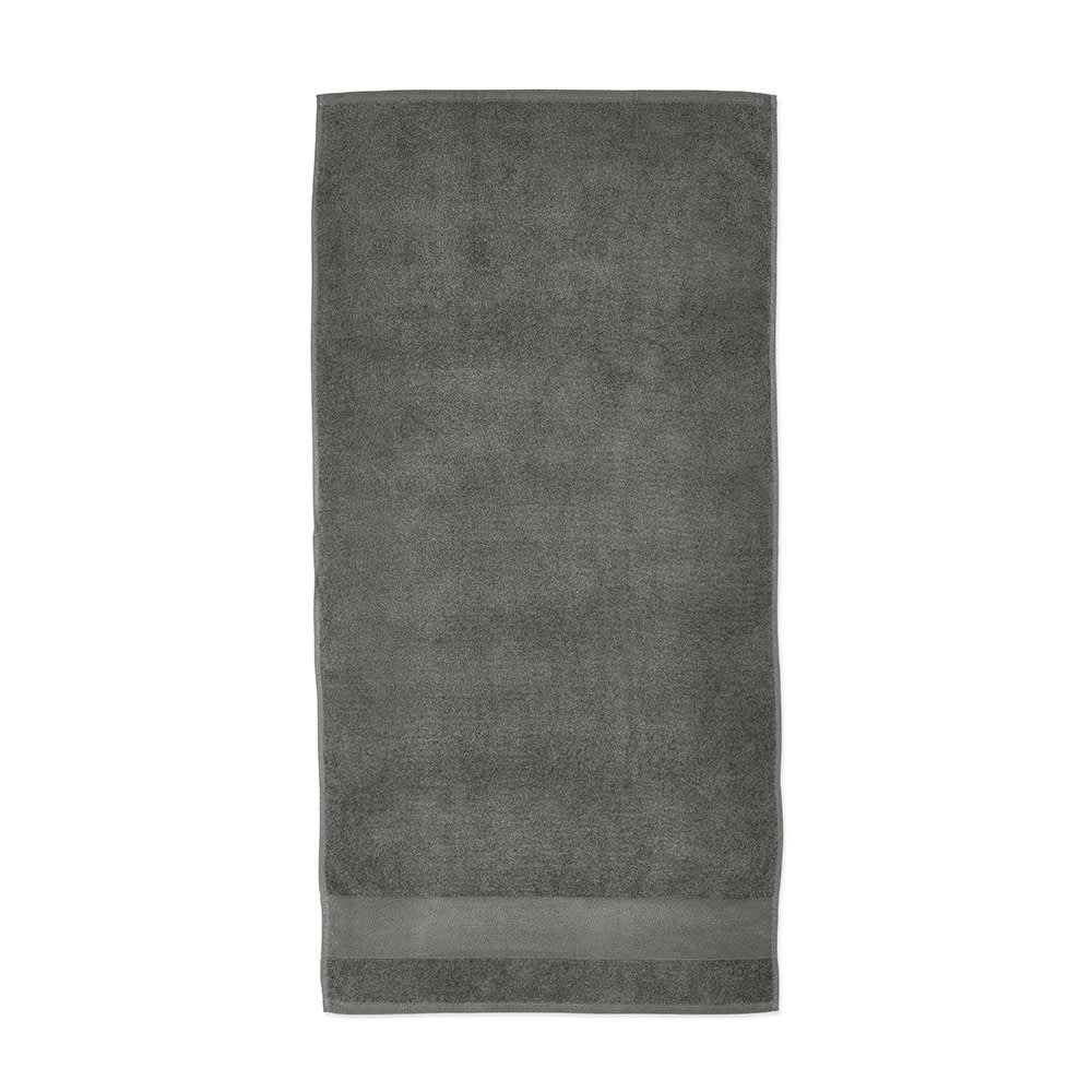 A grey cotton towel with a textured finish and a hemmed border. It has a logo on the side.