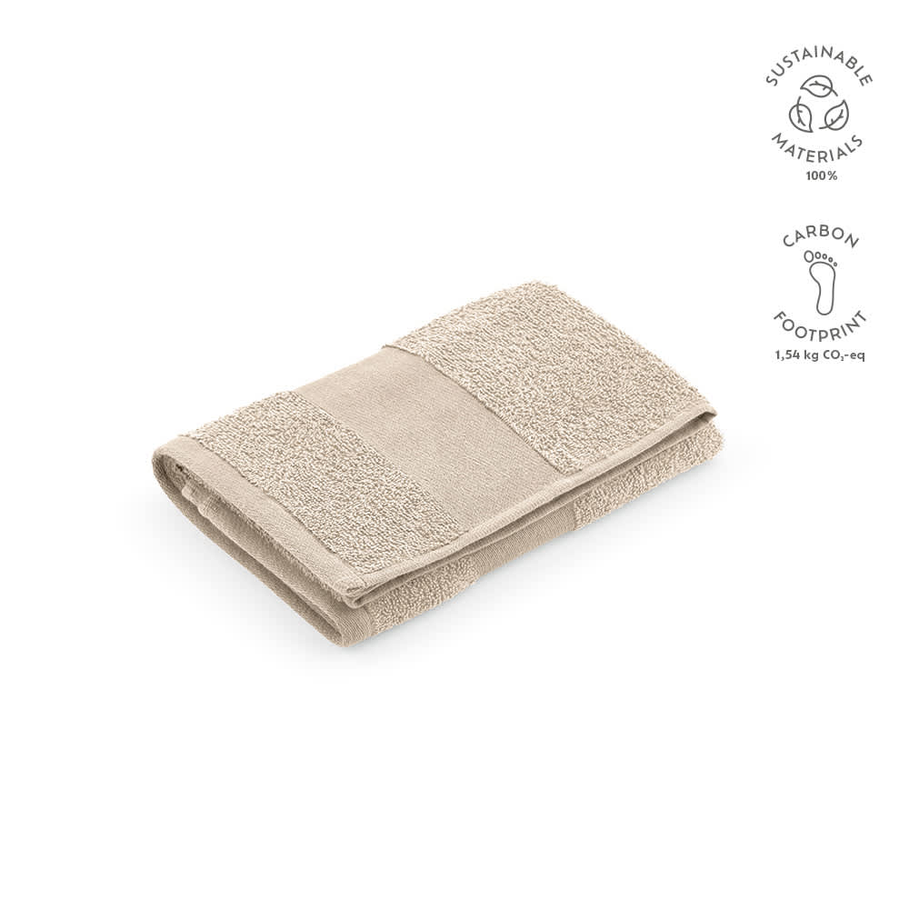 A folded towel in a beige colour, featuring textured sections and a logo. Made from sustainable materials.