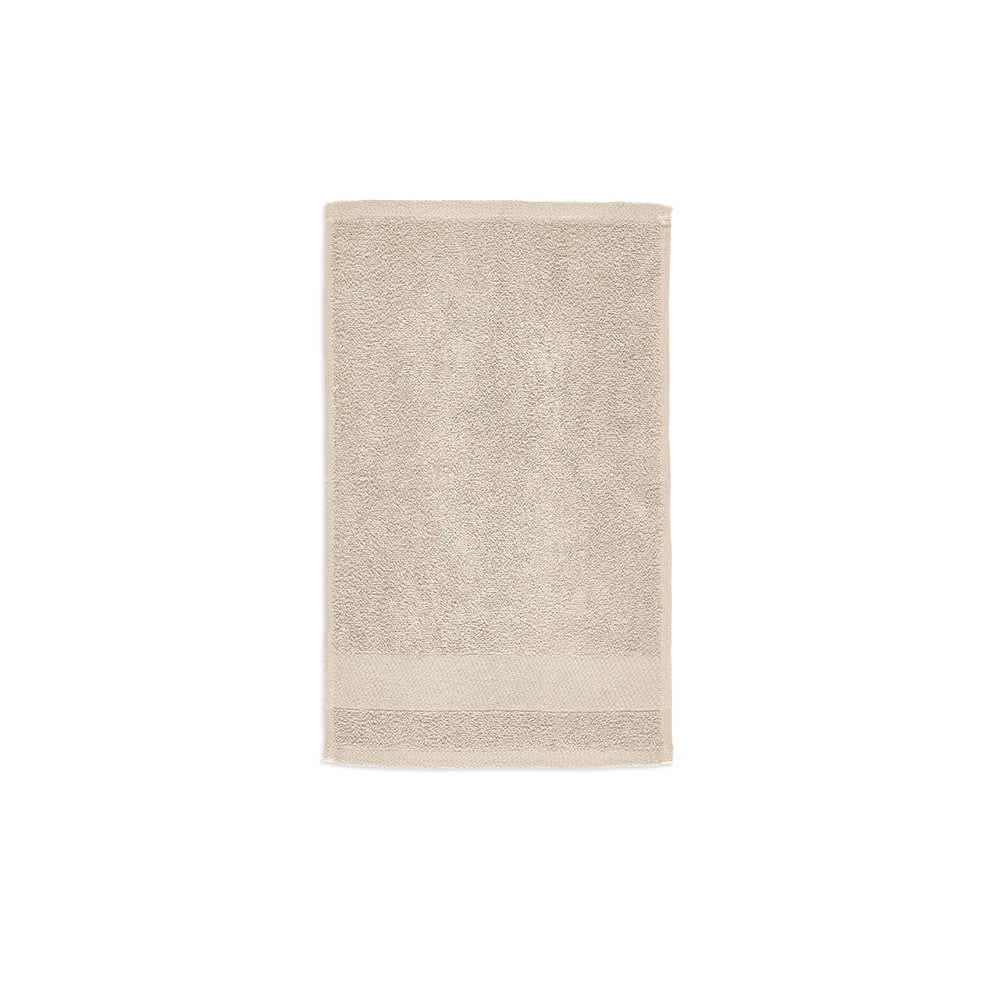 A light beige cotton towel with a textured surface, featuring a logo at the bottom. Made in Portugal.